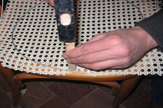 мастер производит ремонт мебели из ротанга