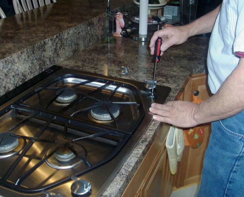 Газовщик прикручивает плиту